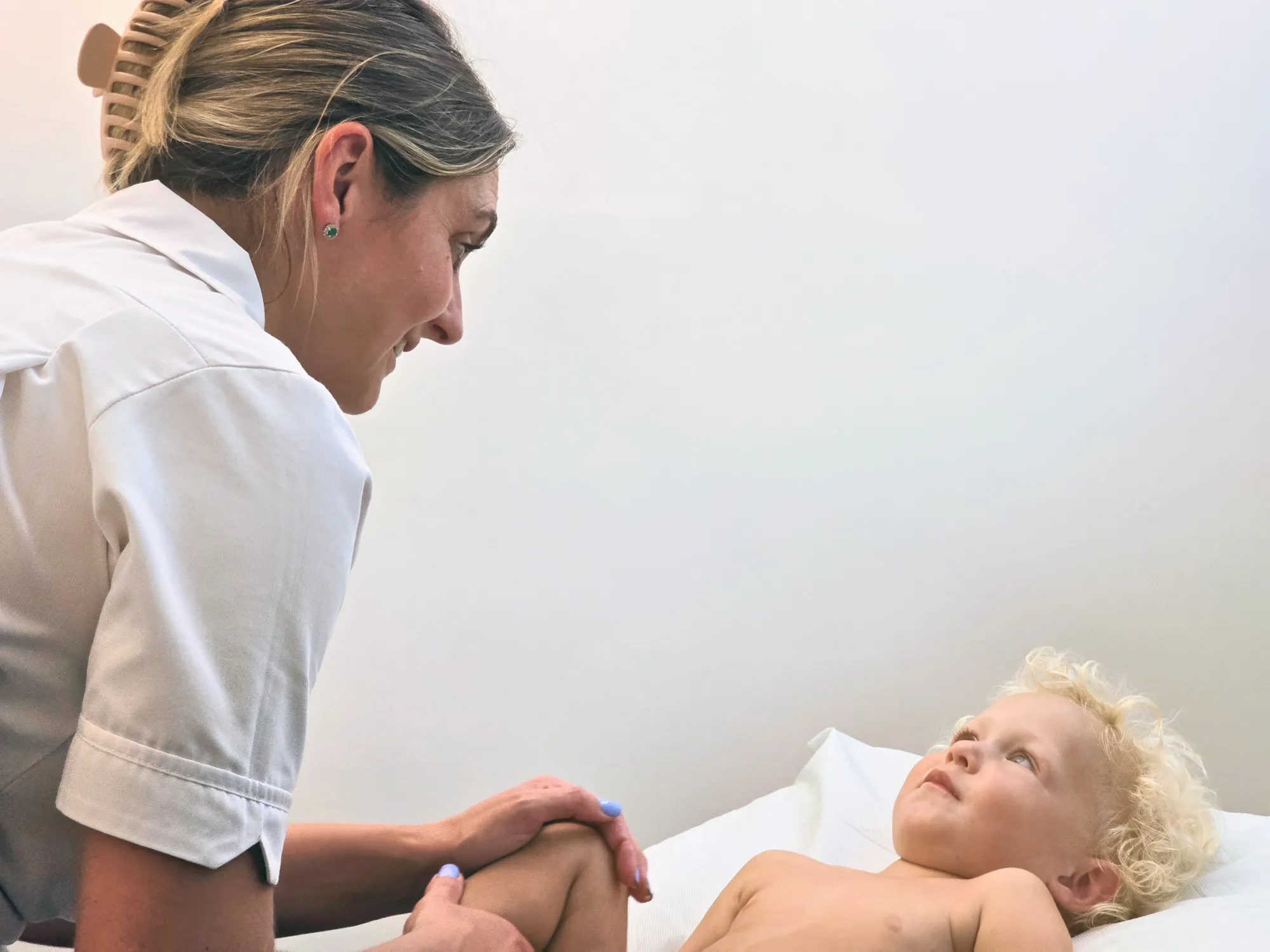 Osteopath gently treating a young child's leg during a paediatric osteopathy appointment